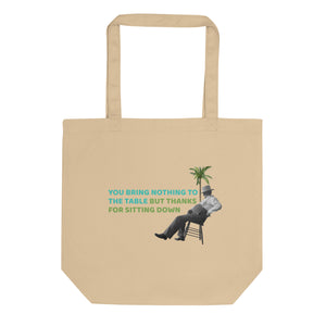 Beige eco tote bag with bold quote 'you bring nothing to the table but thanks for sitting down' print in turquoise and green, featuring a retro sitting men graphic and palm detail , front view, by pepa de mango